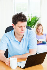 concentrated man working on his laptop with his girlfriend readi
