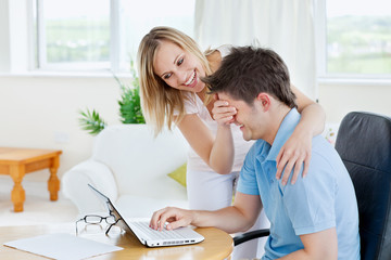 Bright young couple having fun in front of a laptop at home