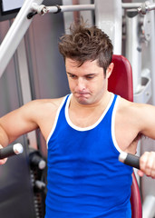 gorgeous man working hard on a bench press in a fitness centre