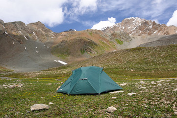 Tent in mountains with sky and clouds