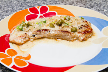 fried steak with caper sauce on the plate