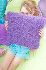 Young girl hiding behind pillow