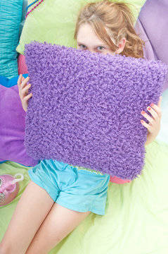 Young girl hiding behind pillow