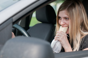 Portrait of young woman eating while driving car