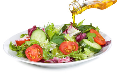vegetable salad with olive oil pouring from a bottle