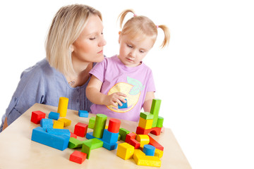 little girl and her mother playing with toy blocks