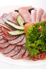 Meat and sausages with parsley and vegetables on white plate