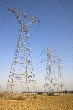 High voltage electricity pylons against blue sky