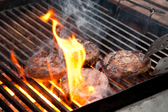 burgers cooking on a flaming barbecue