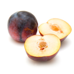 red large plums, one cut in half,  isolated on white