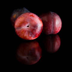 ripe red and purple plum fruits; isolated on black