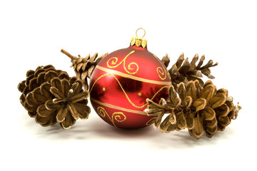 red christmas bauble and pine cones over a white background