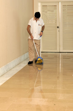 Young housekeeper sweeping floors.