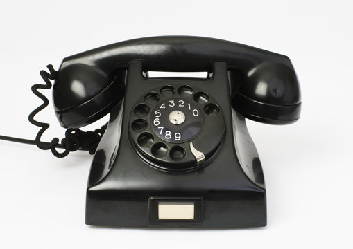 Old classic black bakelite phone on white background