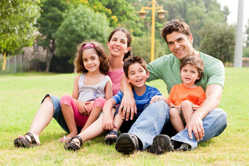 Fototapeta premium Family seated in park and smiling at camera