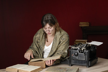 Fototapeta na wymiar woman with antique typewriter reading very old books