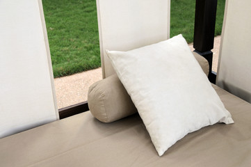Beige bolster and cushion on a canopy bed outside © tobago77