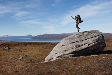 Springender Wanderer auf einem riesigen Felsbrocken