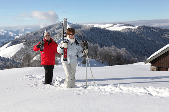Homme et femme seniors marchant avec paire de skis dans la neige