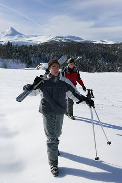 Hommes marchant dans la neige avec paires de skis