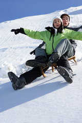 Fototapeta na wymiar Jeune homme et femme faisant de la luge à la neige