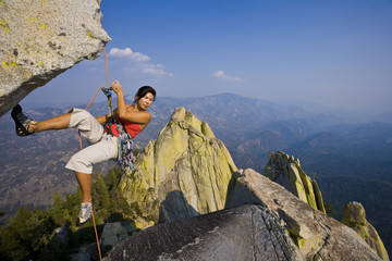 Female rock climber rappelling.