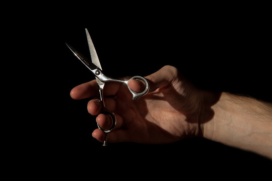 man's hand with hair cutting scissors, isolated on black