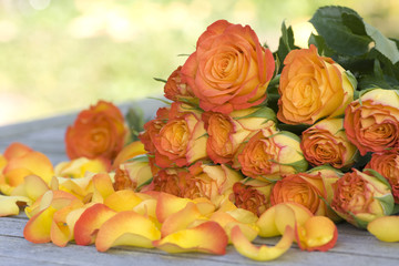 Obraz na płótnie Canvas Beautiful orange roses with petals on a table