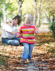 young girl on mother and brother background in autumn park