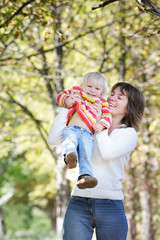 mother and daughter playing in autumn park