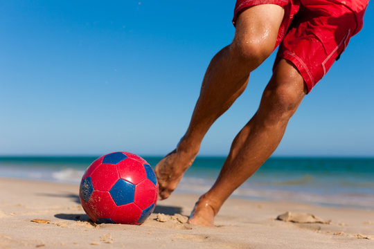 Mann am Strand kickt den Fu&szlig;ball