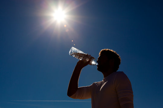 Mann trinkt Wasser aus Flasche unter Sonne