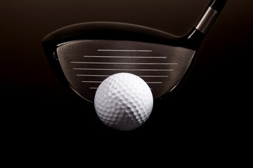 a close-up of a golf driver and golf ball on black