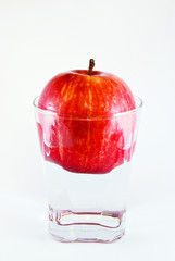 apple in a glass of water isolated on white background