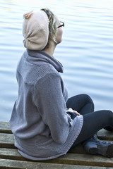 young woman sitting on a pier and watching the lake