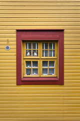 Fototapeta premium Red window on a yellow wall