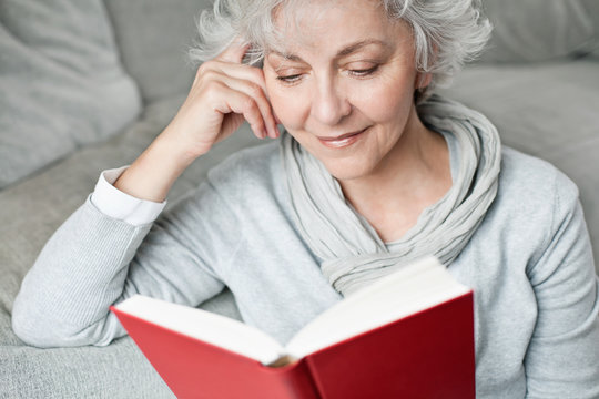 &auml;ltere, attraktive Frau genie&szlig;t ein Buch