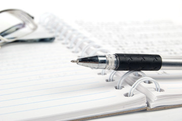 Glasses,pen with notebook on white background