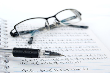Fototapeta premium Glasses,pen with notebook on white background