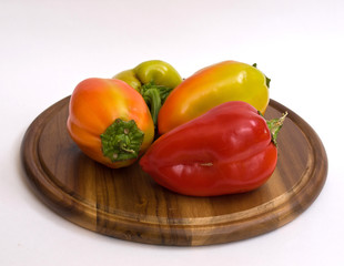 Colorful paprikas on wooden kitchen board isolated