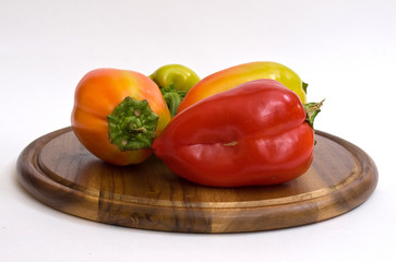Colorful paprikas on wooden kitchen board isolated