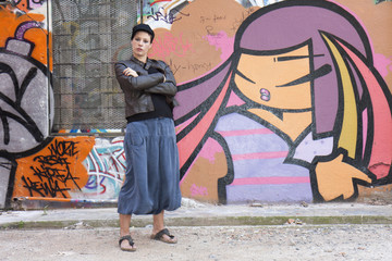 jeune femme posant, bras croisés ,devant un graffiti