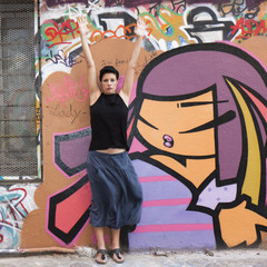 Jeune femme faisant sa gymnastique devant un graffiti
