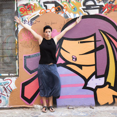 Jeune femme levant les bras devant un graffiti
