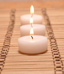 Fototapeta na wymiar Three candles on a bamboo carpet