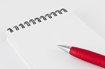 Bolígrafo rojo y libreta blanca