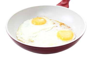 Broken egg frying in a pan isolated on white