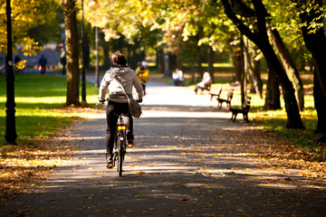 Woman on bicycle in park at fall