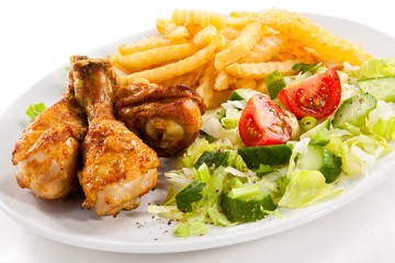 Grilled chicken drumsticks, chips and vegetables