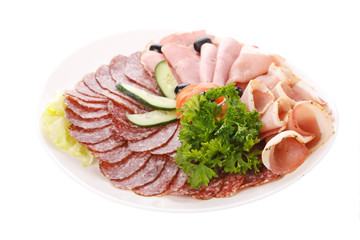 Meat and sausages with parsley and vegetables on white plate